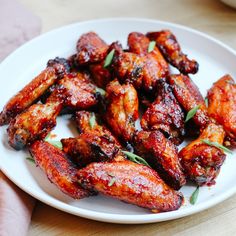 a white plate topped with chicken wings covered in sauce