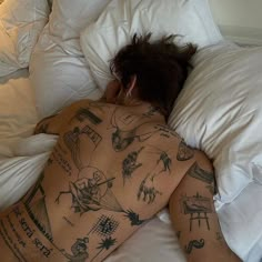 a man laying in bed with tattoos on his back and arms, all over his body