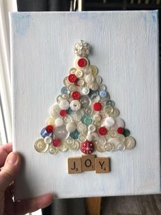 a christmas tree made out of buttons is displayed on a white board with the word joy spelled