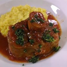 a white plate topped with meat and gravy covered in sauce on top of yellow rice