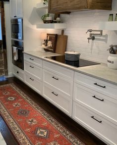 a kitchen with white cabinets and an area rug