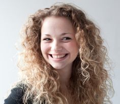 a woman with curly hair smiling at the camera