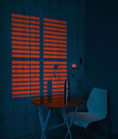 a table with a vase on it in front of a window that has red light coming through the blinds