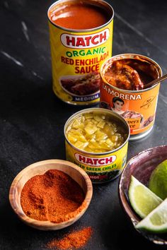 three different types of food in small bowls on a black table with limes and spices