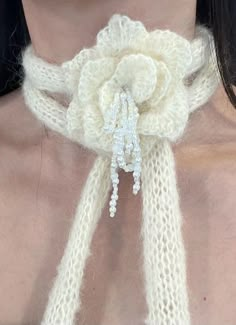 a close up of a woman wearing a white knitted scarf with flowers on it