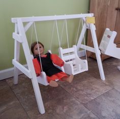 a doll sitting on a swing in a room