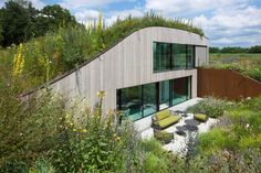 a house with a green roof surrounded by wildflowers and grass on the side