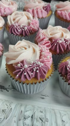 cupcakes with pink and white frosting sitting on a tray