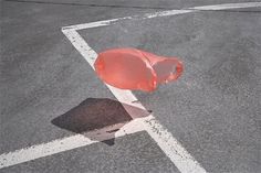 an empty parking lot with a red object on the ground and white lines painted on it