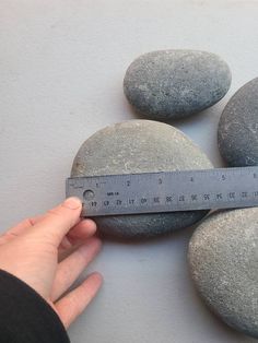 a person is measuring some rocks with a tape