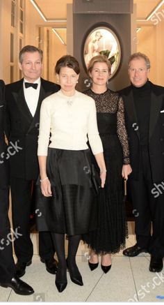 four people in tuxedos standing next to each other wearing formal attire and posing for the camera