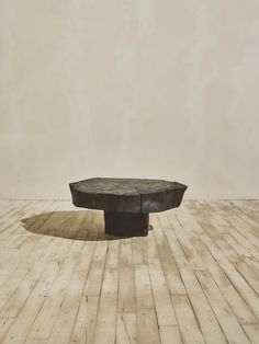 a black table sitting on top of a hard wood floor next to a white wall