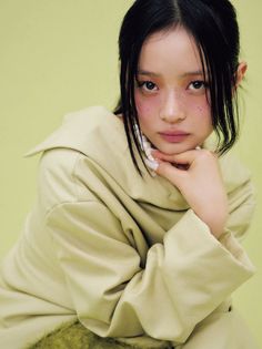 a young woman with black hair and blue eyes wearing a beige kimono posing for the camera