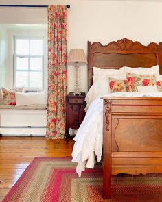 a bed sitting in a bedroom next to a window with curtains on the windowsill