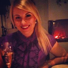 a woman sitting at a table with a glass of wine in front of an open fire place