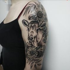 a woman's arm with a deer and sunflowers tattoo on her shoulder