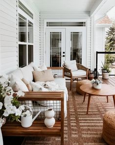 a porch with white furniture and flowers on the table