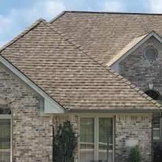 a large brick house with two windows and a roof that has a brown shingles on it