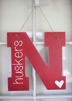 a red wooden sign hanging from the side of a window