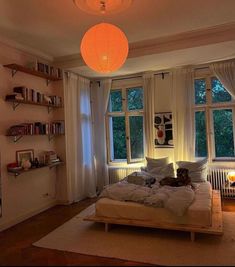 a bedroom with a bed, bookshelf and two lamps hanging from the ceiling