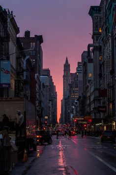 a city street with tall buildings at dusk