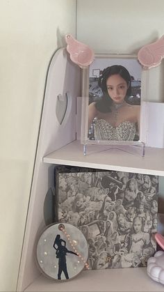 a shelf with pictures and other items on it, including an angel's wings