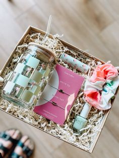 an open box with various items in it on a wooden floor next to someone's feet