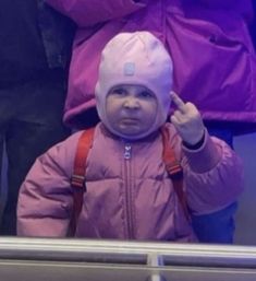 a small child wearing a pink jacket and hat