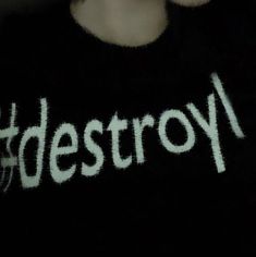 a person wearing a black shirt with the word destroy written in white on it's chest