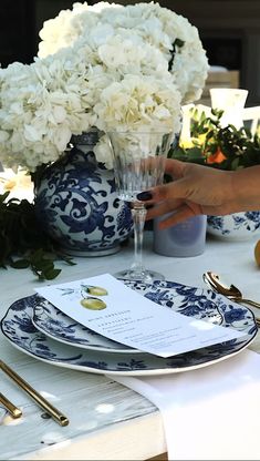 the table is set with blue and white plates, silverware, and floral centerpieces