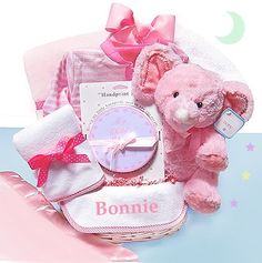 a pink teddy bear sitting on top of a bed next to a baby's diaper