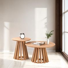 two wooden tables sitting next to each other in front of a window with a clock on it