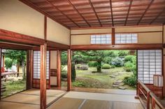 an empty room with wooden doors and windows on the outside, in front of trees