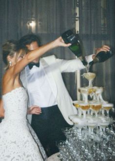 a bride and groom are pouring champagne on their wedding cake