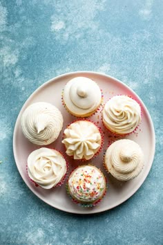 cupcakes with white frosting and sprinkles on a plate