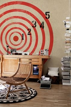 a living room with a chair and a clock on the wall above it, in front of a large bulls eye target