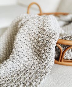 a crocheted blanket laying on top of a bed next to a wooden basket