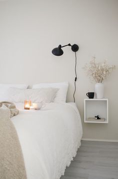 a bedroom with a white bed and two black lamps