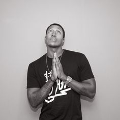 a man standing in front of a white wall with his hands folded up to pray