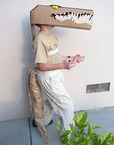 a young boy is dressed up as a cardboard alligator