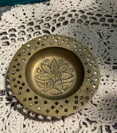 an antique brass plate on a crocheted doily