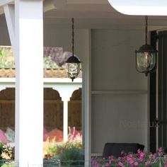 two lights hanging from the side of a building with flowers growing on it's sides