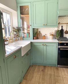 a kitchen with green cabinets and white counter tops, an oven and dishwasher