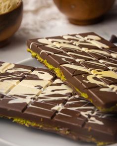 two pieces of chocolate with white and yellow icing on them sitting on a plate