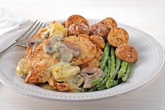 a white plate topped with chicken, potatoes and asparagus next to a fork