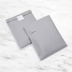 two gray envelopes on a white marble surface