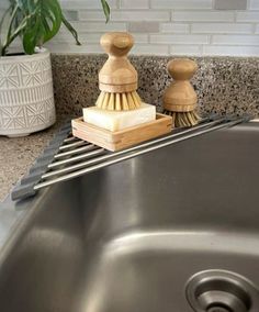 a close up of a kitchen sink with a brush and soap dispenser