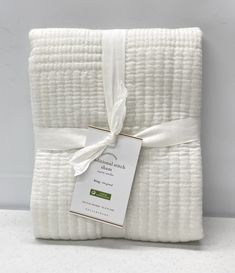 a folded white blanket with a tag on it