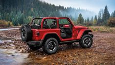 a red jeep is parked in the mud