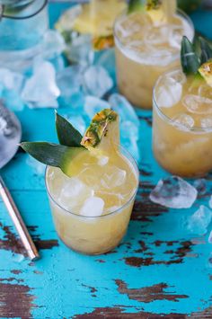 three glasses filled with drinks and garnished with leaves on the rim, sitting on top of ice